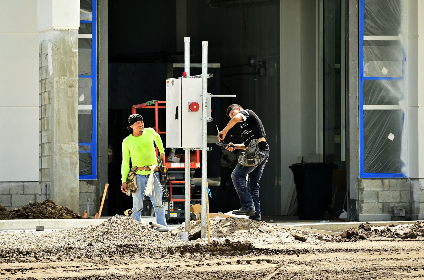 Pracownicy montują szafę elektryczną na budowie